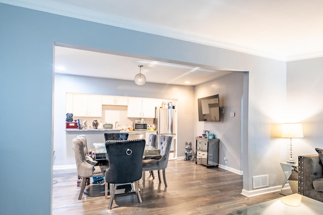 dining area with dark wood-type flooring and ornamental molding