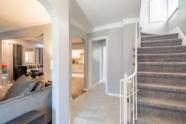 stairs with crown molding and tile patterned floors