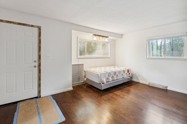 unfurnished bedroom with a textured ceiling and dark hardwood / wood-style flooring