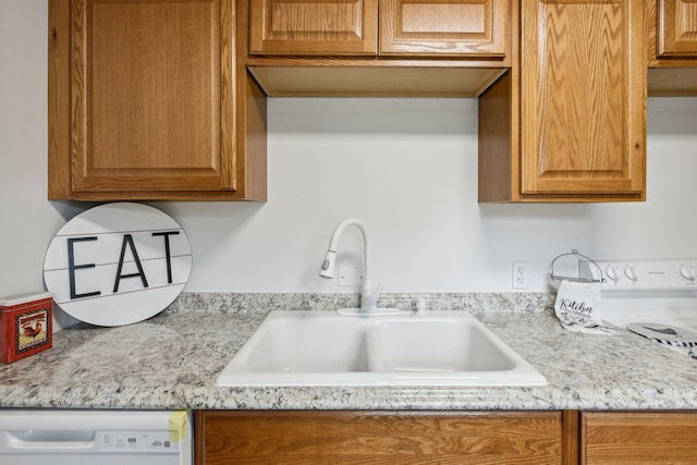 kitchen featuring dishwasher, light stone countertops, and sink