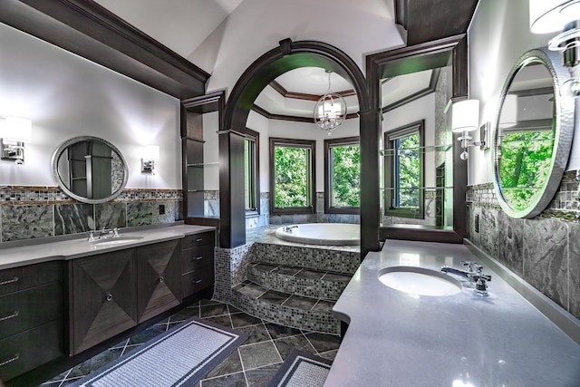 bathroom with vanity, a high ceiling, ornamental molding, a notable chandelier, and tiled bath