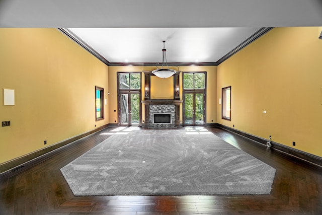 unfurnished living room featuring dark hardwood / wood-style flooring, a stone fireplace, and crown molding