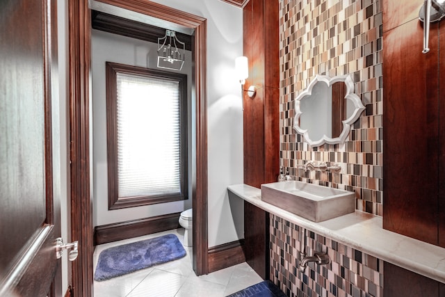 bathroom featuring toilet, decorative backsplash, tile patterned floors, and sink