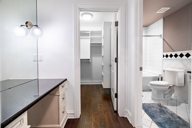 bathroom featuring hardwood / wood-style flooring, vanity, toilet, and tile walls