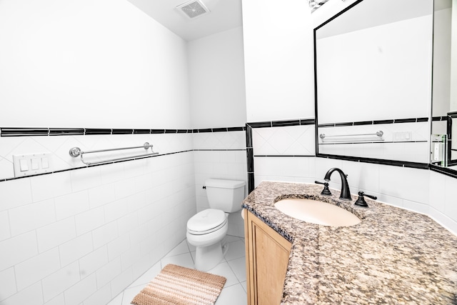 bathroom with tile patterned flooring, vanity, toilet, and tile walls