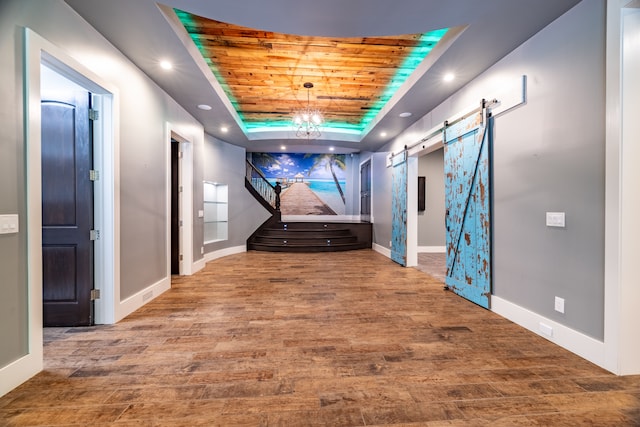 hallway with wood ceiling, a barn door, a raised ceiling, and wood-type flooring