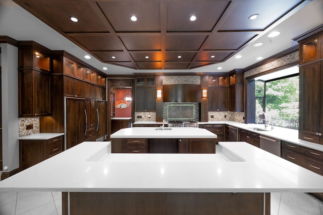 kitchen featuring dark brown cabinetry, stainless steel dishwasher, a large island, and sink