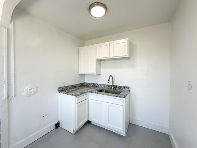3737 Scovel Pl, Detroit, MI 48208 - kitchen with a sink, baseboards, white cabinets, arched walkways, and dark tile patterned floors
