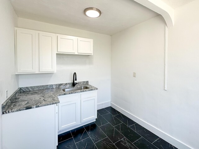 3737 Scovel Pl, Detroit, MI 48208 - kitchen featuring a sink, dark marble finish floors, white cabinets, baseboards, and light stone counters
