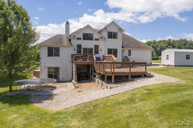 rear view of property featuring a lawn, a storage unit, a deck, and a trampoline