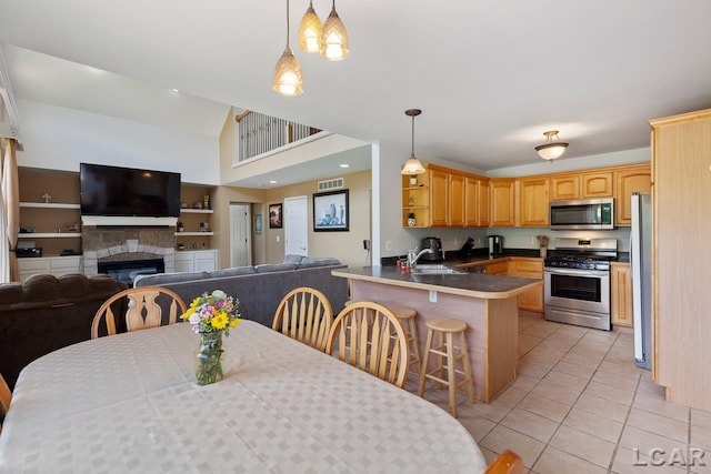 dining space featuring lofted ceiling, light tile patterned floors, sink, and a tiled fireplace