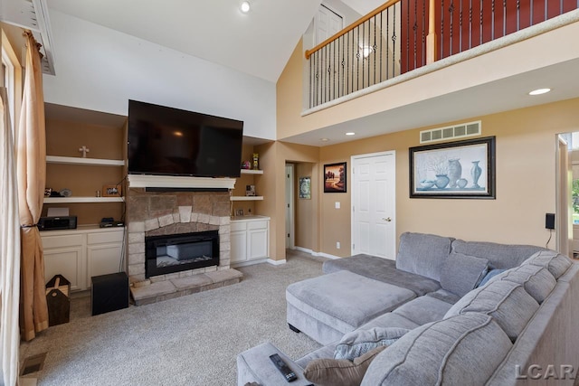 carpeted living room with a stone fireplace, built in shelves, and high vaulted ceiling