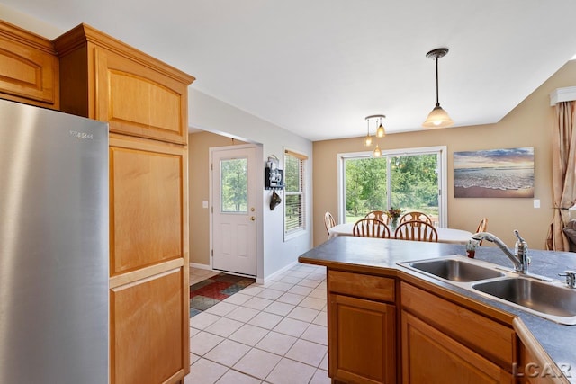 kitchen with pendant lighting, stainless steel fridge, sink, and a wealth of natural light