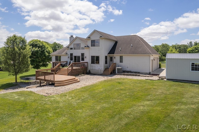 rear view of property featuring a lawn, an outbuilding, and a wooden deck