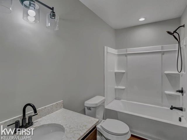 full bathroom featuring vanity, bathing tub / shower combination, and toilet