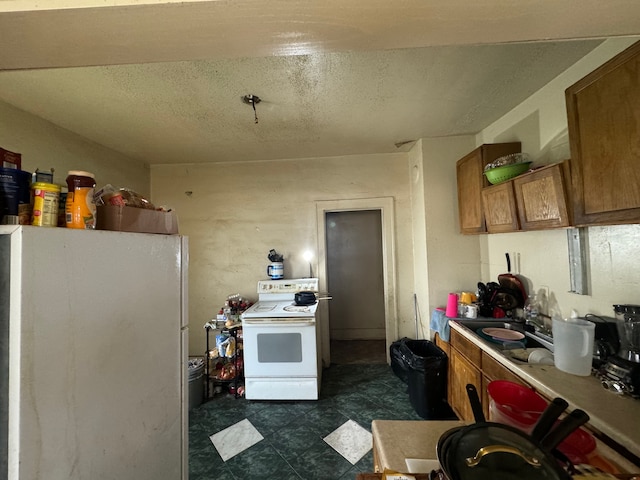 kitchen with a textured ceiling, sink, and white appliances