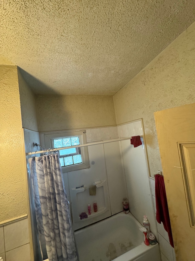 bathroom featuring a textured ceiling and shower / tub combo with curtain