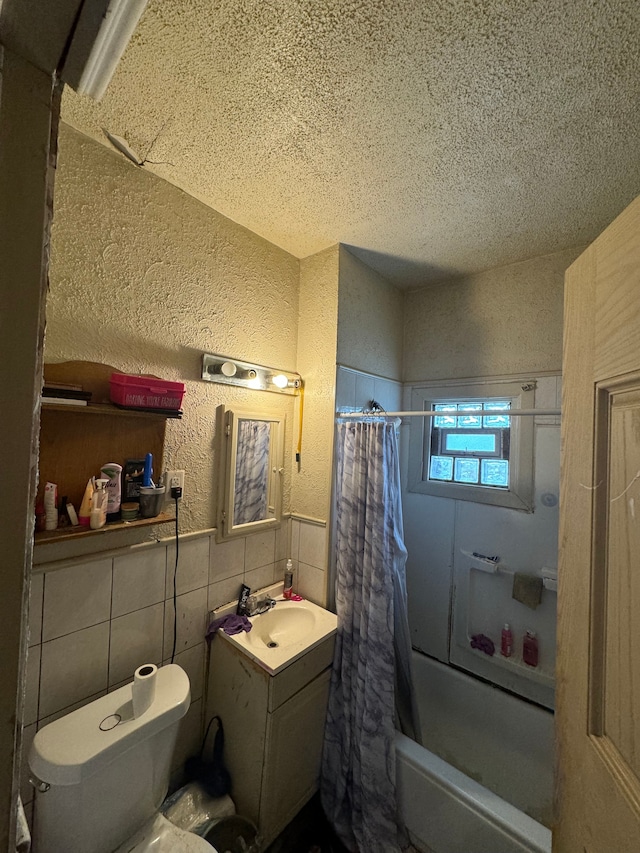 full bathroom with shower / bath combination with curtain, vanity, a textured ceiling, tile walls, and toilet