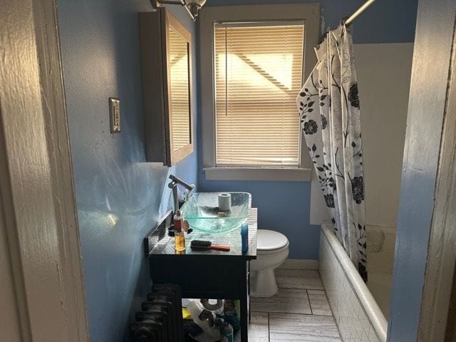 full bathroom with radiator, shower / bath combo with shower curtain, vanity, and toilet