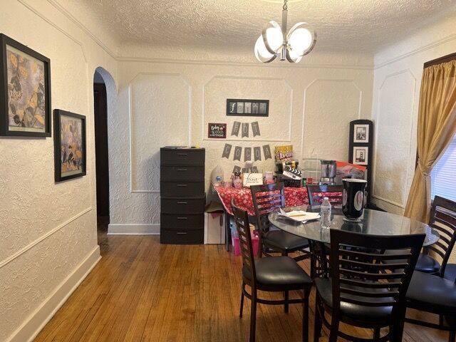 dining space with a textured ceiling, dark hardwood / wood-style flooring, and a notable chandelier