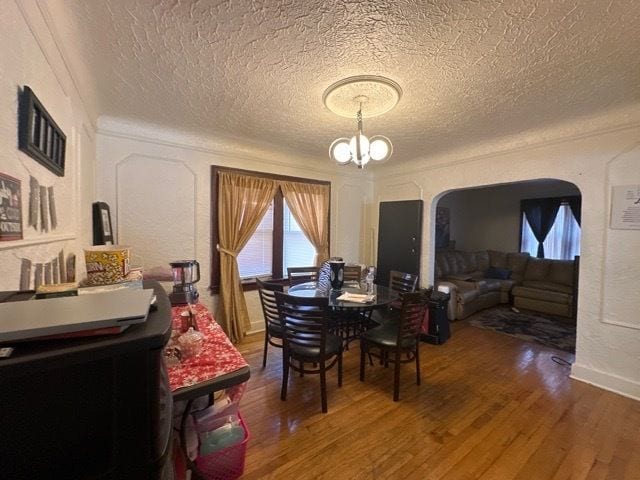 dining room with a textured ceiling, a notable chandelier, and hardwood / wood-style flooring