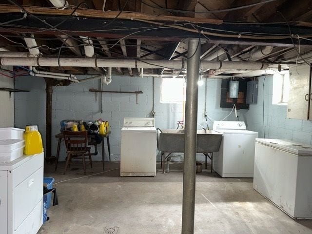 basement with white fridge, washing machine and dryer, sink, and electric panel