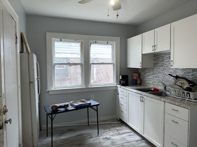 kitchen with white cabinets, ceiling fan, white fridge, and sink