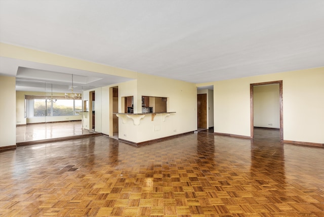 unfurnished living room with an inviting chandelier and parquet flooring