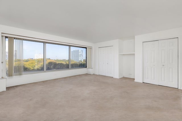 unfurnished bedroom with light carpet and multiple closets