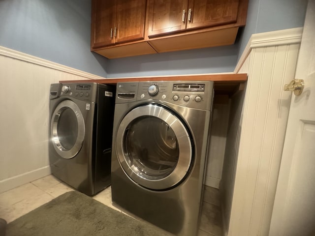 washroom featuring washer and dryer, cabinets, and light tile patterned floors