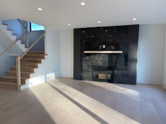 unfurnished living room with a tile fireplace and hardwood / wood-style floors