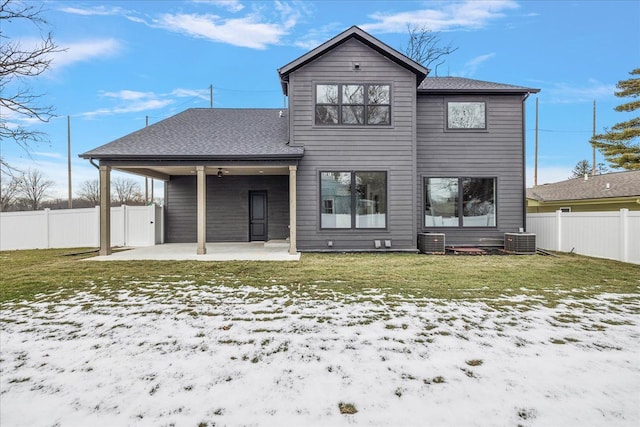 snow covered house featuring central AC, a patio area, and a lawn