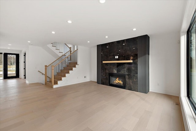 unfurnished living room with a tile fireplace and light hardwood / wood-style flooring