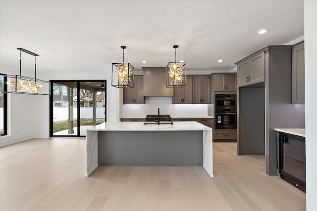 kitchen featuring pendant lighting, sink, gray cabinetry, decorative backsplash, and light hardwood / wood-style floors