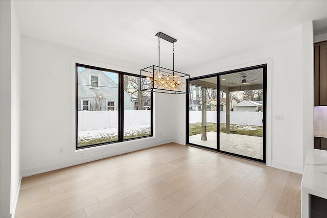 unfurnished dining area with an inviting chandelier and light hardwood / wood-style flooring