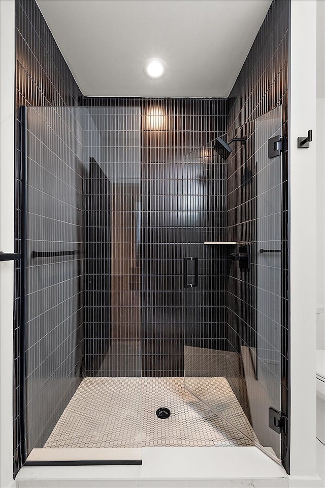 bathroom with a tile shower and toilet