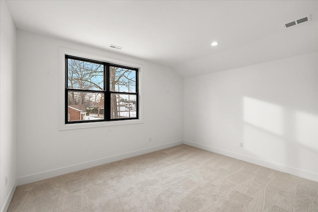 unfurnished room featuring vaulted ceiling and light colored carpet