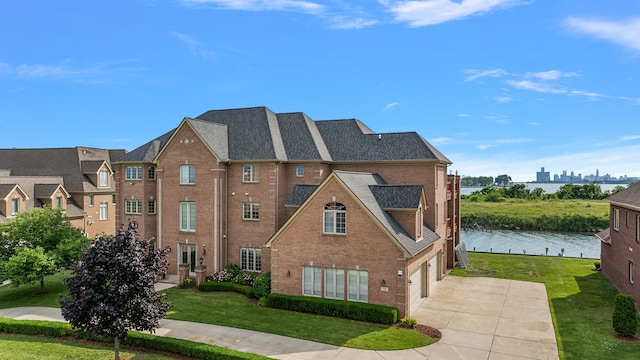 view of front of house featuring a garage, a water view, and a front lawn