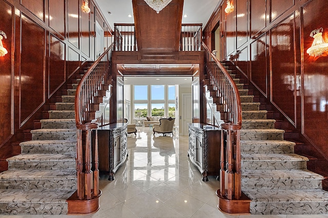 stairway with tile patterned flooring and a towering ceiling