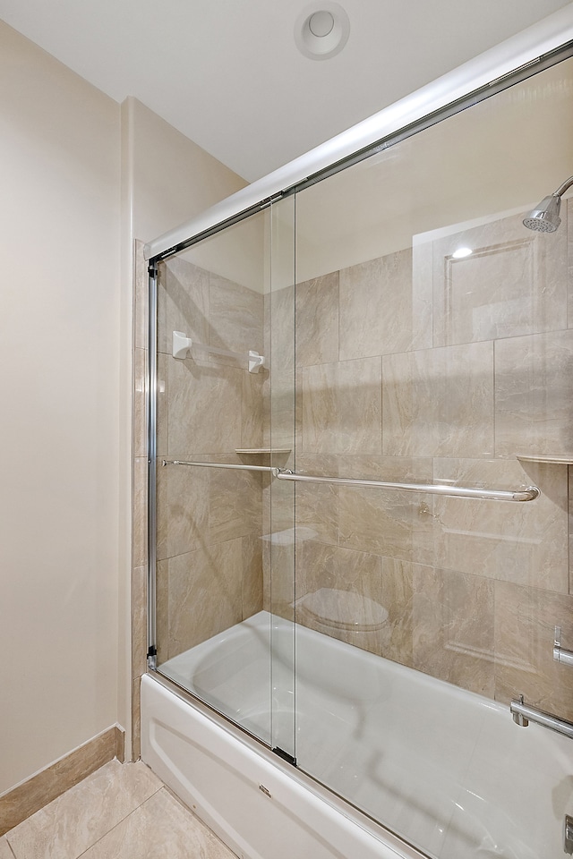 bathroom featuring tile patterned flooring and combined bath / shower with glass door