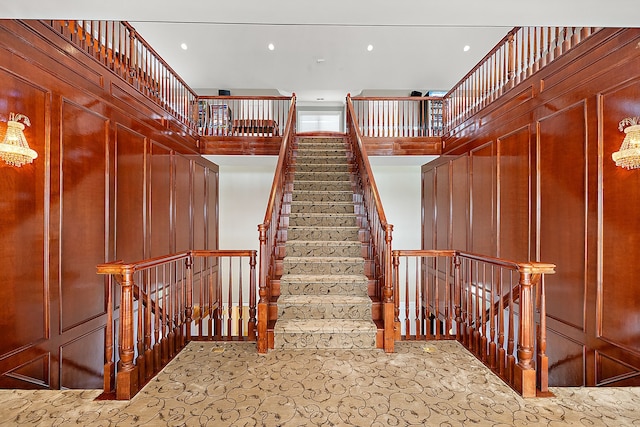 staircase featuring wooden walls and a high ceiling