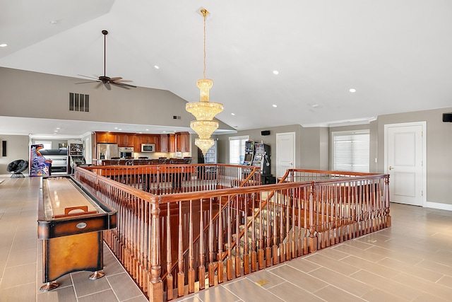 interior space with ceiling fan with notable chandelier, lofted ceiling, and appliances with stainless steel finishes