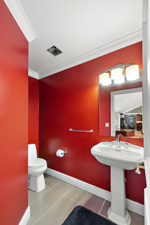 bathroom featuring ornamental molding and toilet