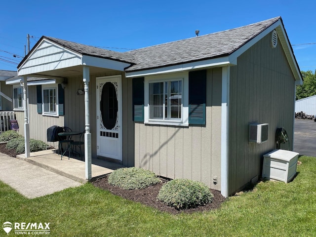 view of front of house featuring a front lawn and a wall mounted AC