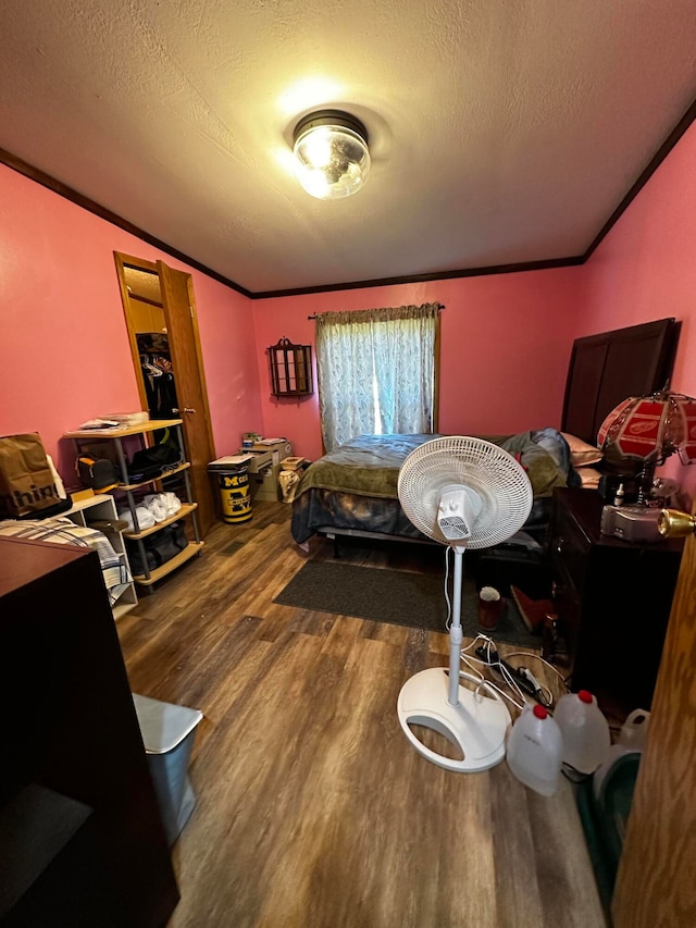 bedroom featuring hardwood / wood-style floors, ornamental molding, and a textured ceiling