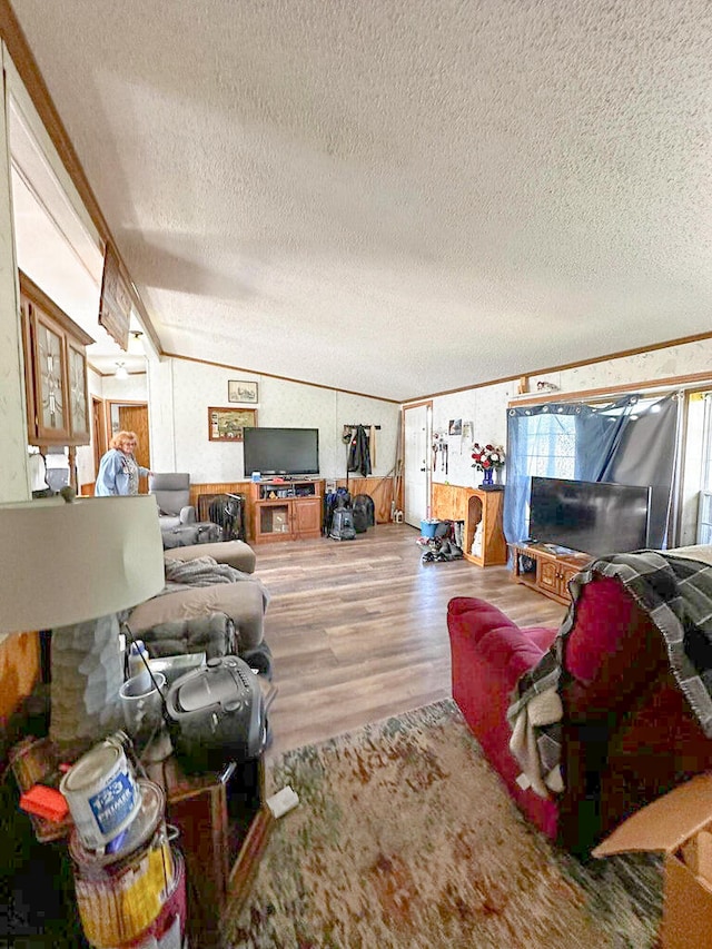 living room featuring hardwood / wood-style floors, a textured ceiling, crown molding, and lofted ceiling