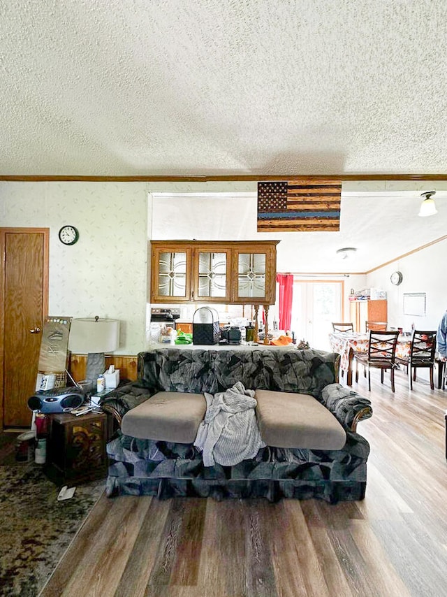 living room with hardwood / wood-style floors, a textured ceiling, and crown molding