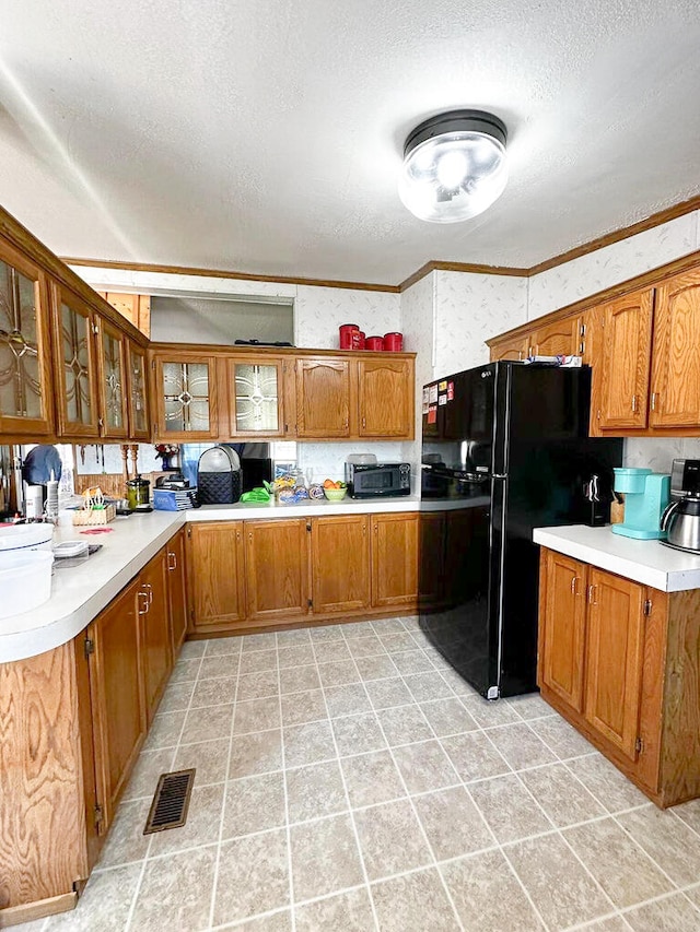 kitchen with black fridge, a textured ceiling, and ornamental molding