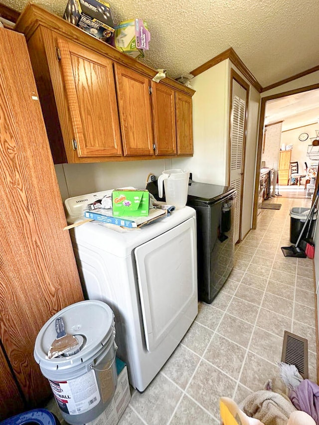 laundry area with cabinets, separate washer and dryer, crown molding, a textured ceiling, and light tile patterned floors