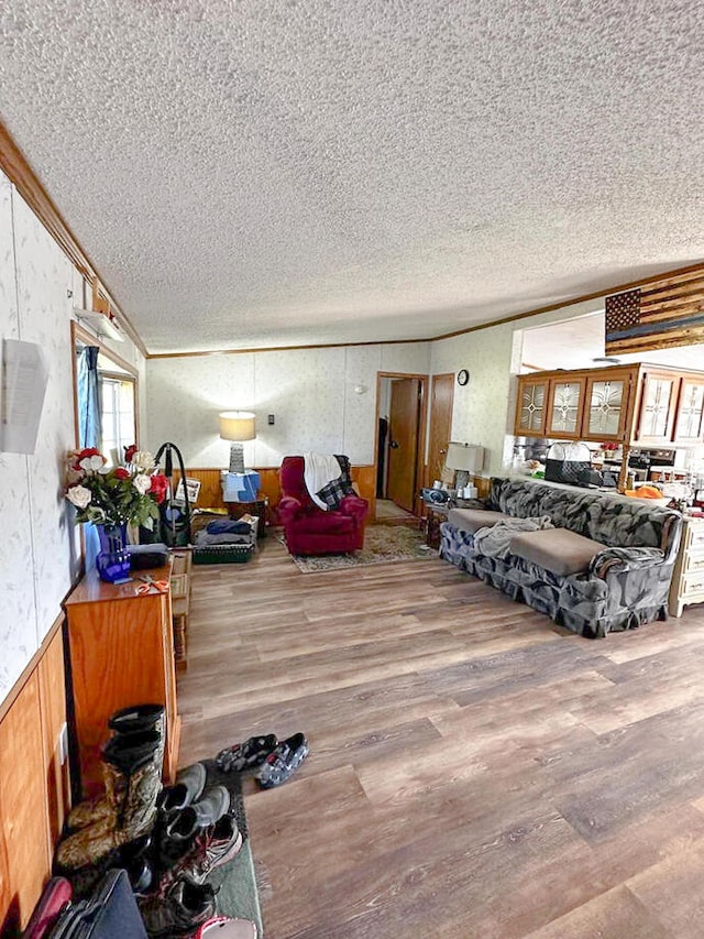 living room with wood-type flooring, a textured ceiling, and ornamental molding